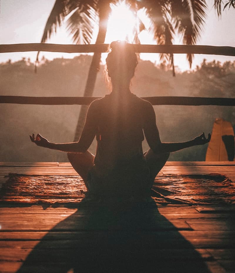 Gün doğumunda lotus pozisyonunda meditasyon yapan kadın silueti